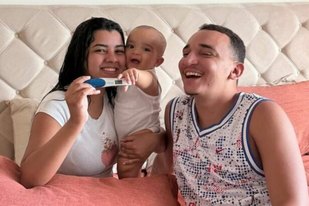 João Gomes e Ary Mirelle, com o filho no colo e mostrando o teste da segunda gravidez