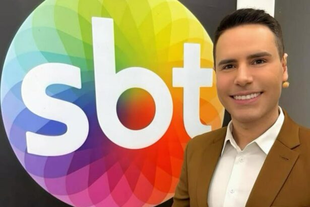 Logo do SBT no quadro do camarim onde Luiz Bacci aparece de terno marrom e microfonado