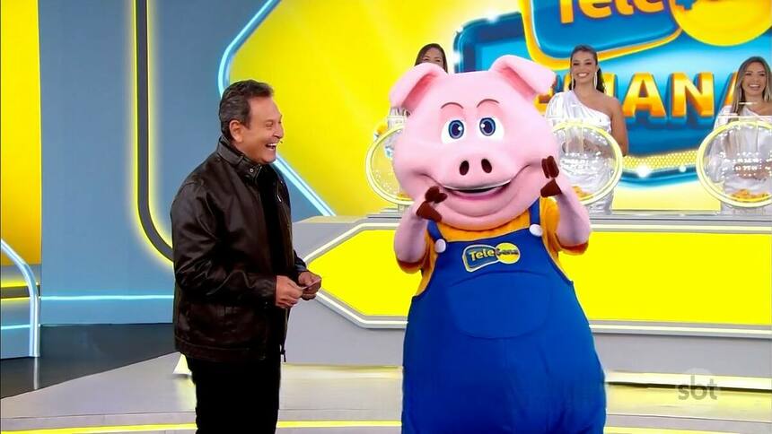 Luiz Ricardo sorrindo ao lado do porquinho no cenário da Tele Sena Semanal