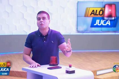 Marcelo Castro em frente a bancada do seu programa Alô Juca que tem uma sirene no cenário do programa da TV Aratu/SBT
