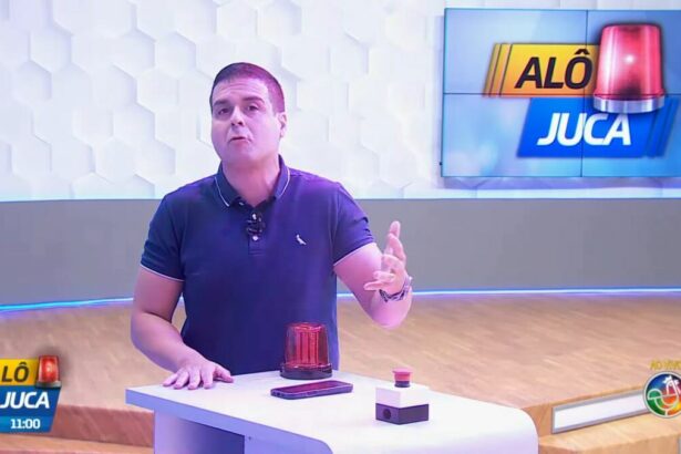 Marcelo Castro em frente a bancada do seu programa Alô Juca que tem uma sirene no cenário do programa da TV Aratu/SBT