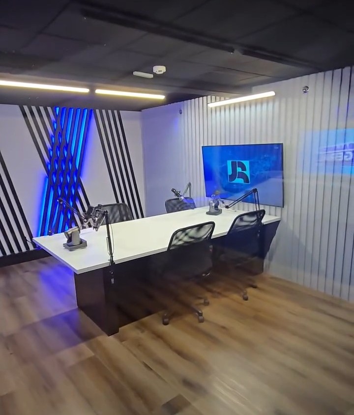 Cenário de Podcasts da RECORD Brasília com piso madeirado e telão com o logo do JR
