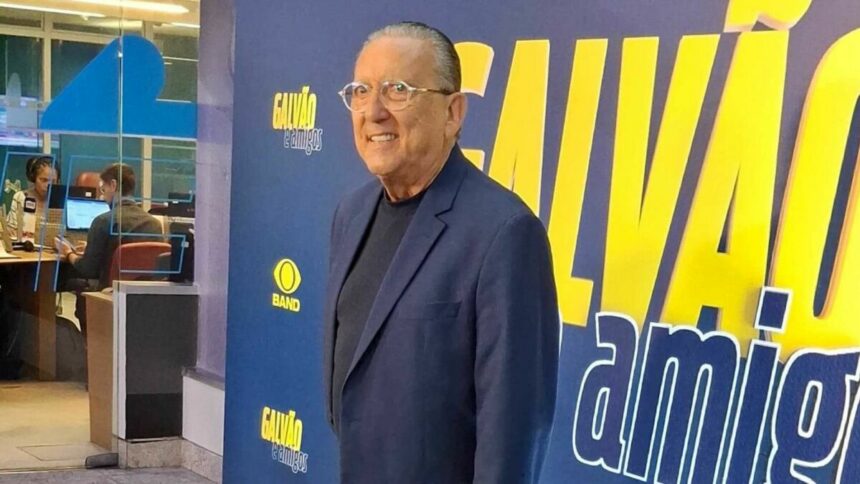 Galvão Bueno em frente a um banner na coletiva do Galvão e Amigos