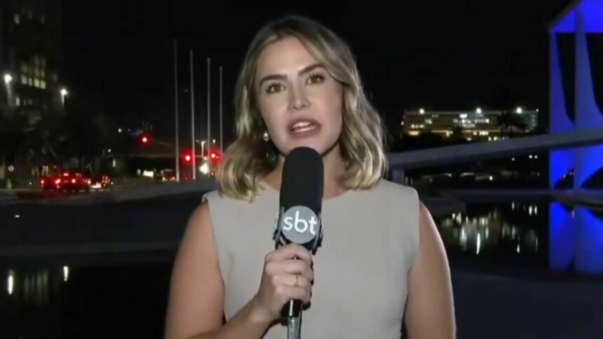 Larissa Alvarenga durante entrada ao vivo no SBT Brasil, segurando o microfone da emissora