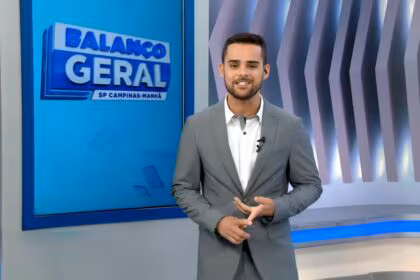 Lucas Carvalho de terno cinza e sorridente, no centro do cenário do Balanço Geral Manhã Campinas na RECORD