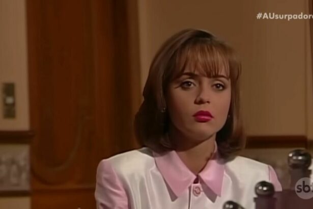 Paulina com roupa rosa em cena da novela A Usurpadora. Ela está olhando para um espelho de maquiagem