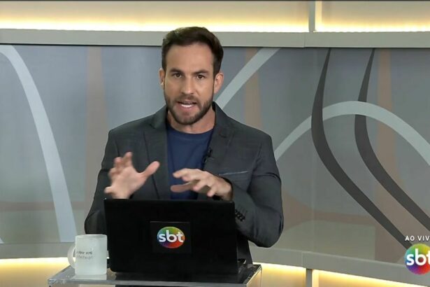 Daniel Adjuto com as mãos levantadas sobre o notebook no cenário do SBT Brasília
