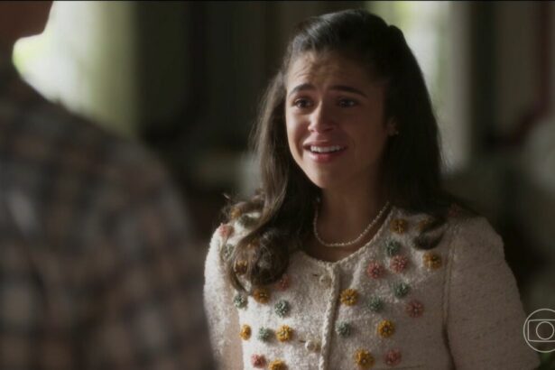 Bia com roupa branca florida, olha para Beto e sorrir em cena da novela Garota do Momento