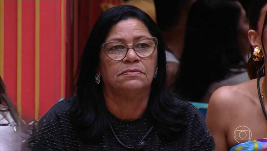 Delma olha sério para o telão onde Tadeu aparece na sala do BBB 25