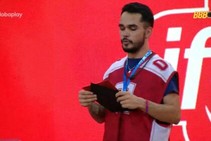 João Pedro ler o castigo do monstro com o colar da imunidade no pescoço no gramado do BBB 25