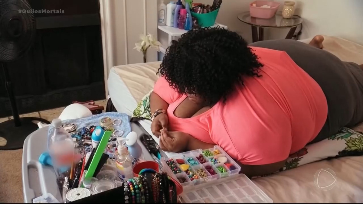 Octavia deitada na cama e com dificuldade para se levantar