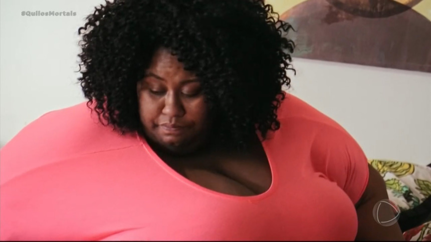 Octavia de blusa rosa mostrando o quanto está acima do peso em cena de Quilos Mortais