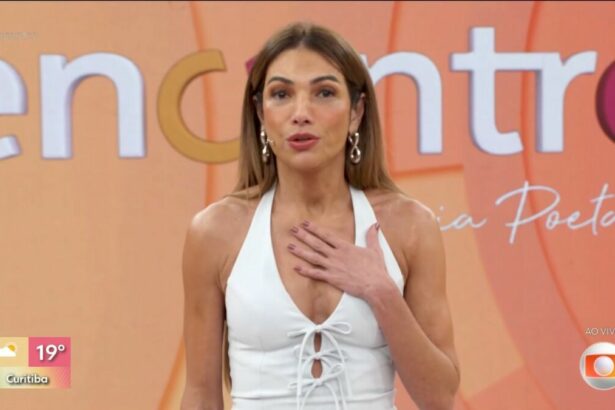 Patrícia Poeta de vestido branco e com a mão no peito no palco do Encontro