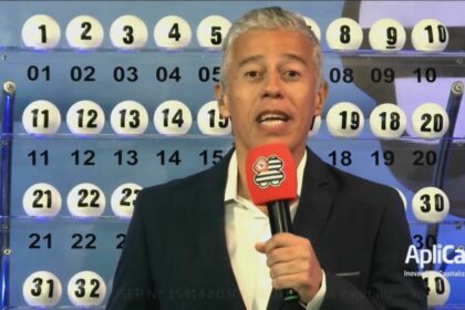 Apresentador segura o microfone do São Paulo dá Sorte, em frente ao painel com as bolas do sorteio