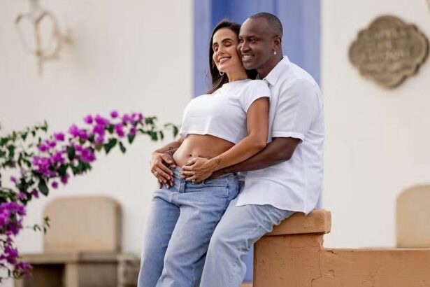 Thiaguinho acaricia barriga de grávida de Caro Peixinho, os dois estão sorridentes e um jardim
