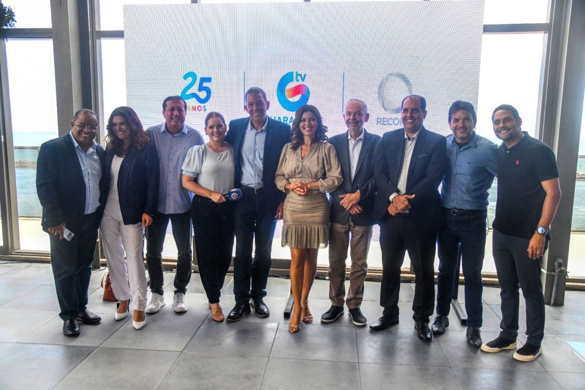 Apresentadores da TV Guararapes RECORD em frente ao telão com o logo das emissoras