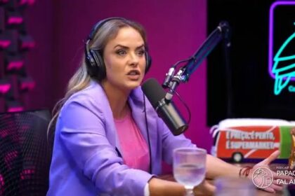 Juliana Silveira de terno lilás e blusa rosa em frente a um microfone de podcast onde revelou denúncia de assédio em novela da RECORD
