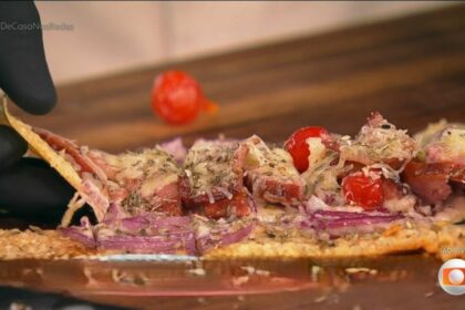 Pizza de calabresa, bacon e pimenta biquinho na base de madeira do programa é de casa