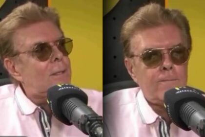 Jornalista Silvio Batalha com óculos de sol em frente ao microfone da Rádio Metrópole FM