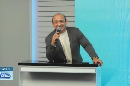 Beto Rêgo segura microfone de mão em cima da bancada do Balanço Geral PI