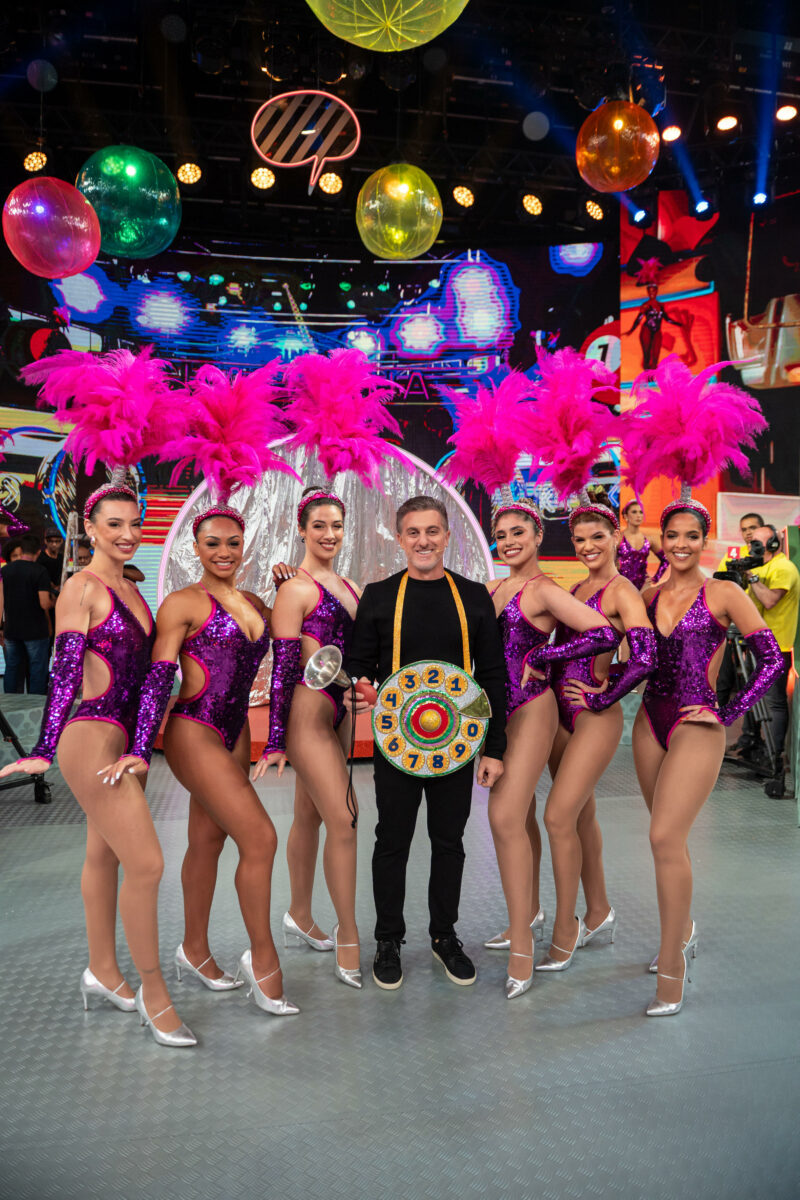 Luciano Huck vestido de Chacrinha ao lado de bailarinas vedestes no palco do Domingão especial de 60 anos