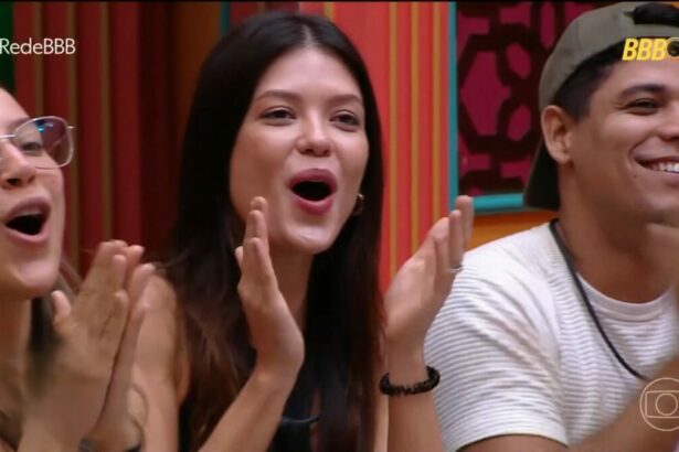 Renata, Vitória Strada e Guilherme batem palma sentados no sofá da sala do BBB 25 ao descobrirem prêmio final