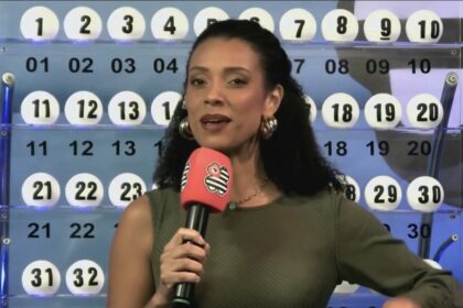Apresentadora do São Paulo dá Sorte em frente ao painel com as bolas do sorteio do dia 27 de abril