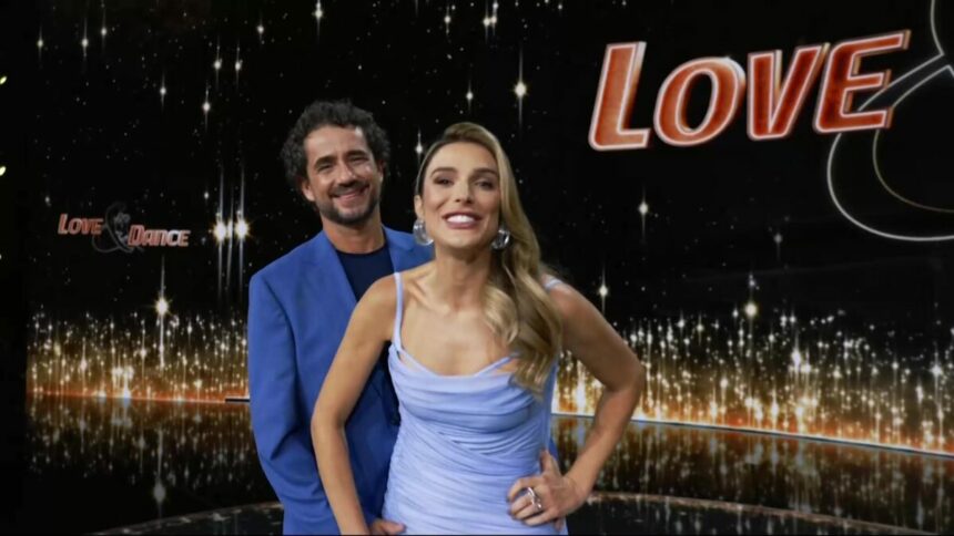 Felipe Andreoli e Rafa Brites em pé, no palco do Love e Dance, eles estão sorridentes