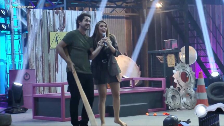 Rafa Brites e Felipe Andreoli, com um bastão em mãos, em trecho de prova do Power Couple Brasil 7