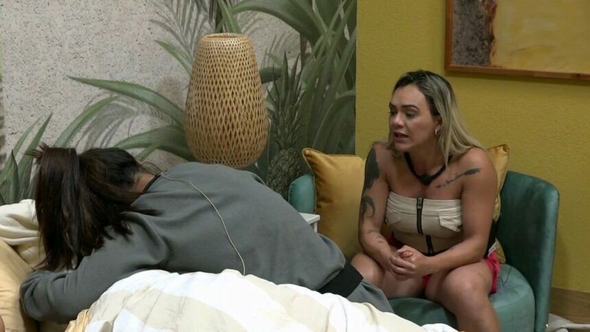 Sentada numa cadeira, Ana Paula olha para Adriana chorando na cama enquanto defende Dhomini no Power Couple Brasil 7