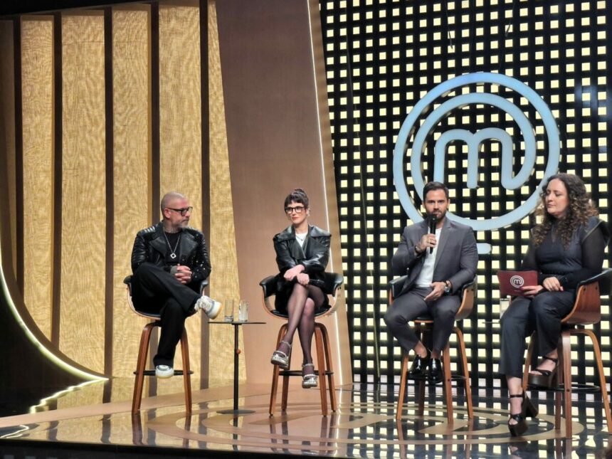 Henrique Fogaça, Helena Rizzo, Diego Lozano e a diretora Marisa Mestiço sentados em banquinhos no palco do novo cenário do MasterChef Brasil 2025