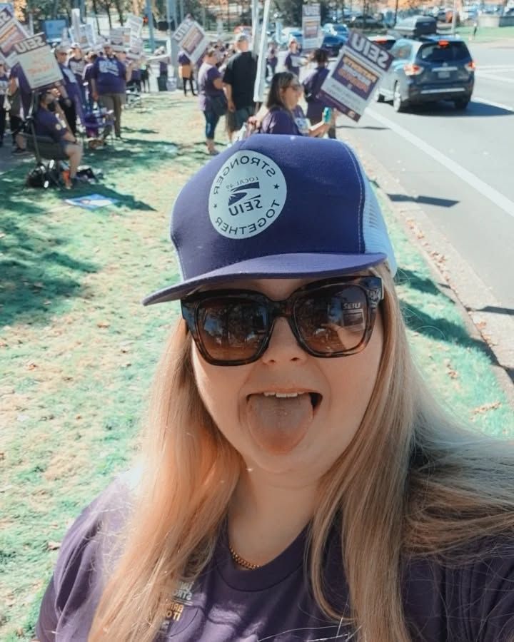 Maja usando boné azul e ósculos escuros. Ela mostra a língua