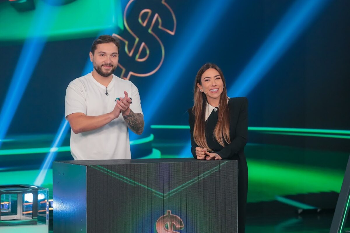 Novo participante do Show do Milhão ao lado de Patricia Abravanel. Ele veste blusa branca e ela um vestido preto