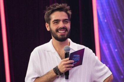 João Guilherme Silva com microfone e ficha nas mãos, em trecho do Programa do João na Band