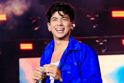 Léo Foguete, vestindo uma jaqueta azul, sorridente, em trecho de apresentação no São João de Petrolina