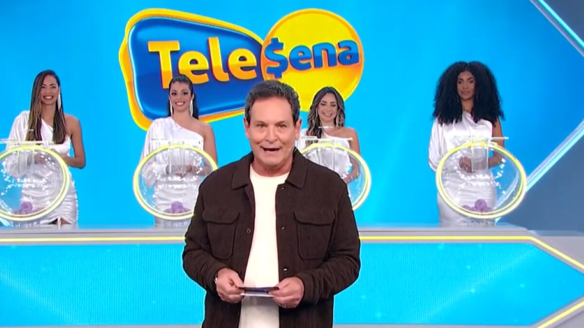 Luis Ricardo caminha no cenário do sorteio da Tele Sena Semanal. O cenário está com artes gráficas na cor da modalidade