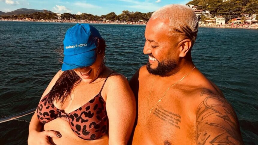 Tati Machado e marido o em trecho de foto na gravidez, em passeio na praia