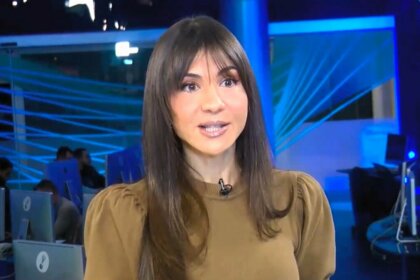 Amanda Klein em pé no meio da redação do RedeTV! News