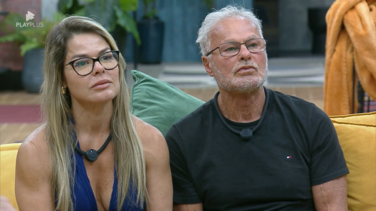 Cris ao lado de Kau sentados no sofá da mansão 