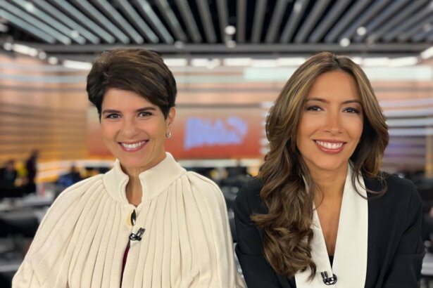 Mariana Godoy e Paloma Poeta sorridentes, em foto posada, na frente da bancada do Fala Brasil