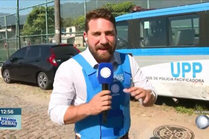 Rael Policarpo segura microfone da RECORD em uma rua do Rio de Janeiro ao lado onde acontece um acidente com duas motos