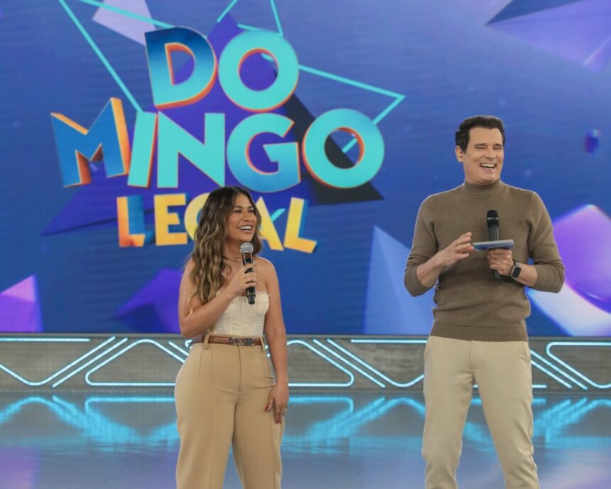 Simone Mendes ao lado de Celso Portiolli no palco do Domingo Legal. Os dois estão sorrindo