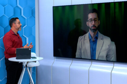 Eduardo Miranda conversa com um especialista no telão do cenário do Aparecida Debate
