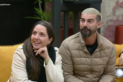 Carol e Radamés sentados no sofá ao acompanhar o resultado da Prova dos Casais no Power Couple