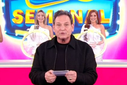 Luis Ricardo segura o bilhete rosa da Tele Sena Semanal edição 60 na frente dos globos e das assistentes de palco