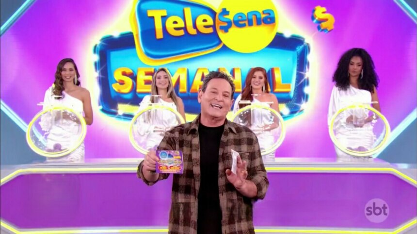 Apresentador Luís Ricardo segura o bilhete da Tele Sena Semanal edição 62. O cenário está todo lilás, na cor do bilhete