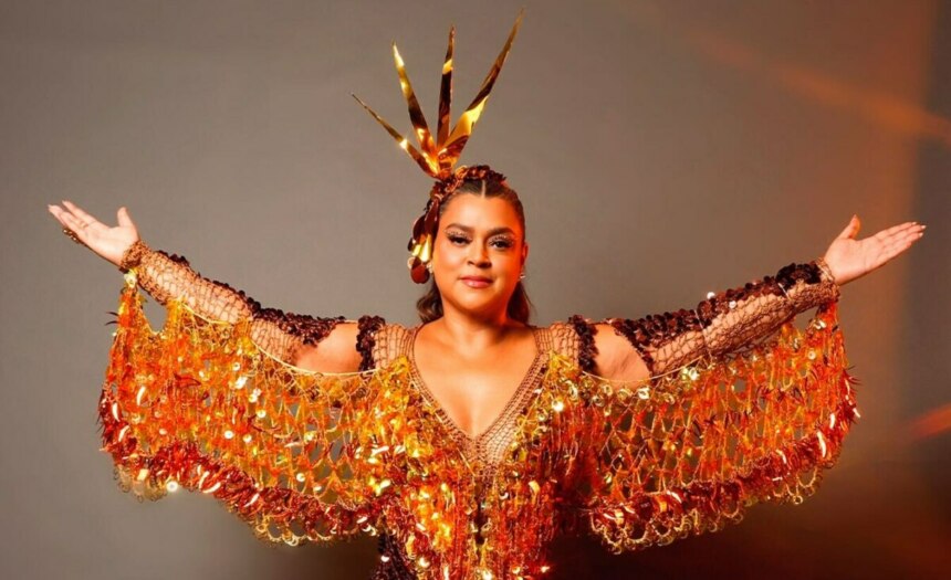 Preta Gil de roupa dourada brilhante e com os braços abertos