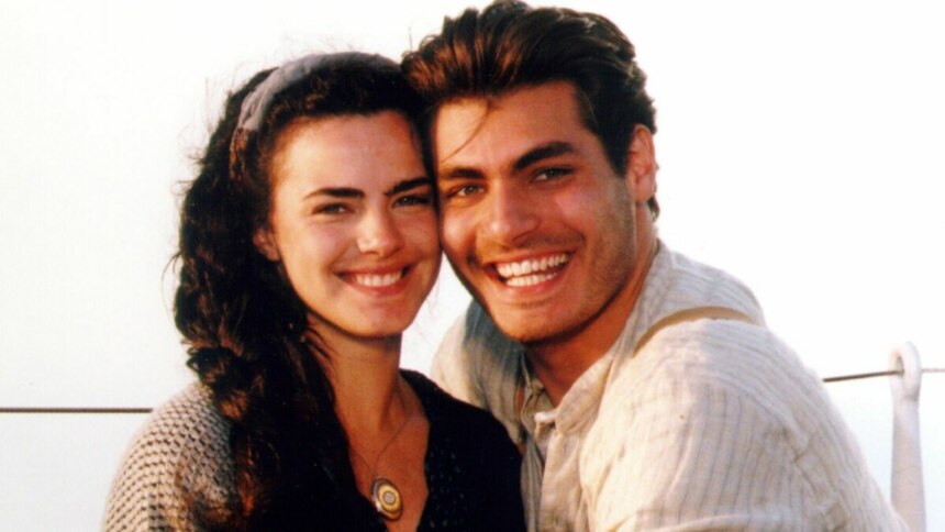 Os atores Ana Paula Arósio e Thiago Lacerda em um close-up, sorrindo alegremente. Ele usa uma camisa clara com suspensórios e ela tem um casaco escuro e uma faixa de cabelo. A foto, com estilo de época, é uma imagem de divulgação da novela "Terra Nostra".