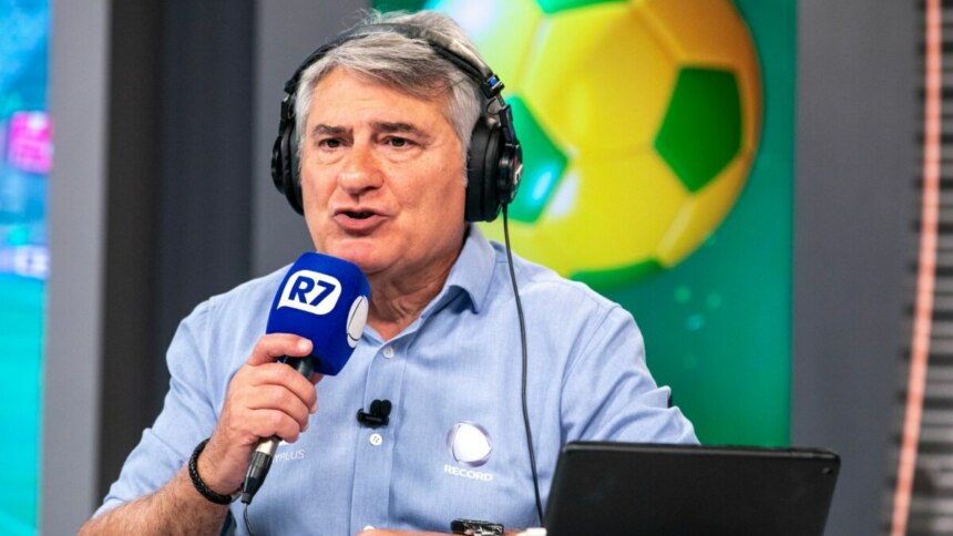 O narrador Cléber Machado em um estúdio da Record. Ele usa fone de ouvido e segura um microfone, falando durante uma transmissão esportiva.