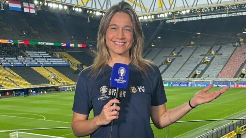 A apresentadora Fernanda Gentil sorri para a câmera, segurando um microfone com o logo da 'CazéTV'. Ela está em um estádio de futebol, e o nome do arquivo a associa ao canal de TV.